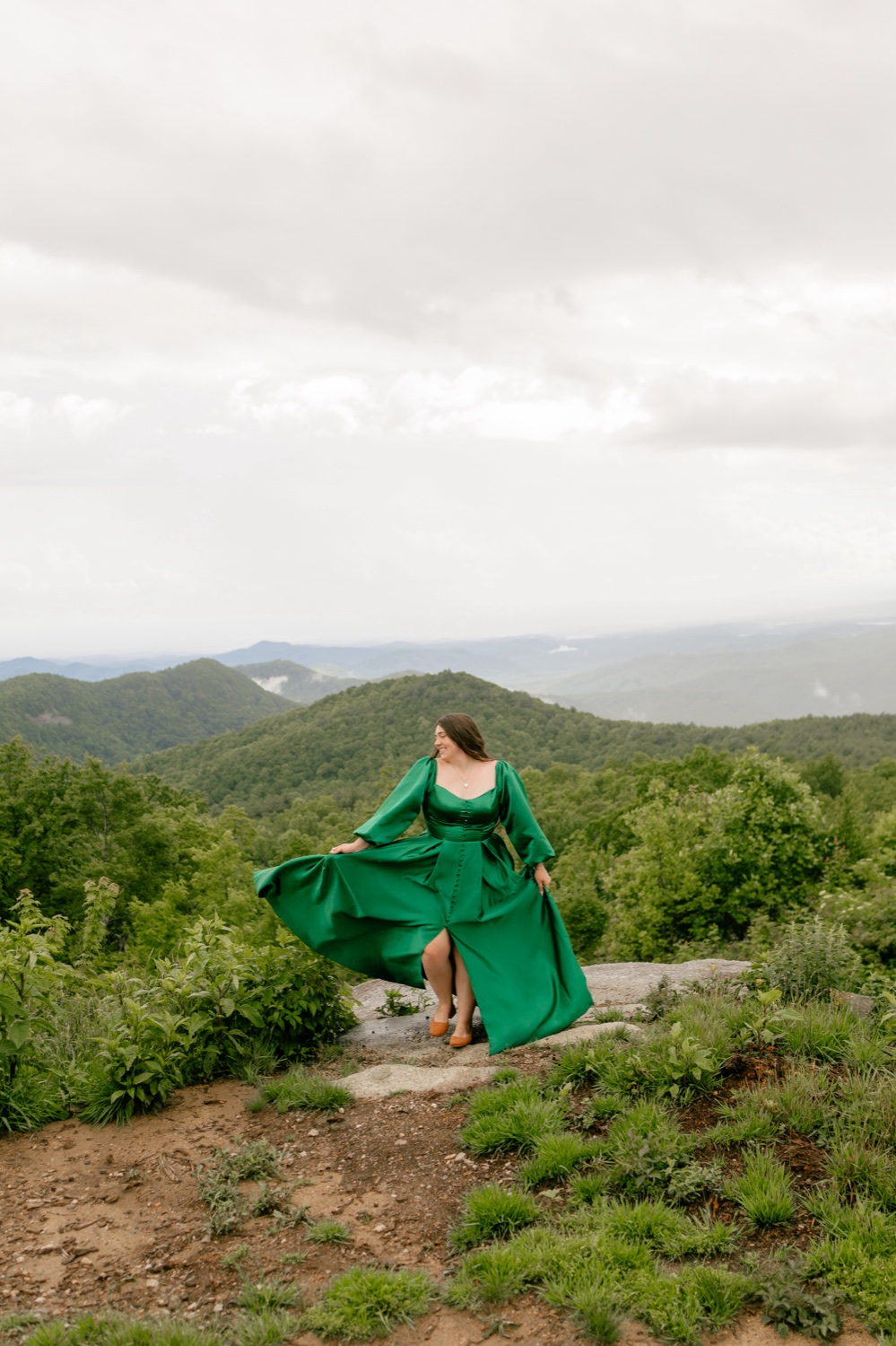Makayla Rendon, the photographer behind Rendon Photography, in an emerald gown on a mountain overlook